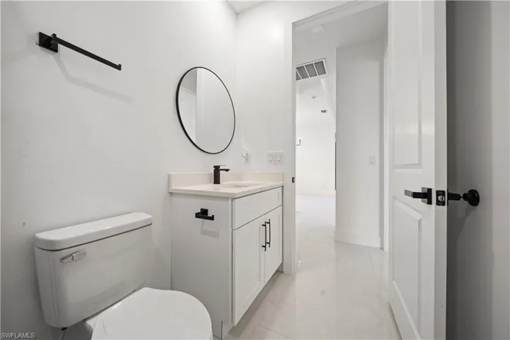 Half bathroom with marble look tiles, toilet, and vanity