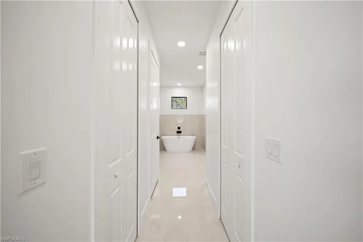 Corridor with recessed lighting and tile walls