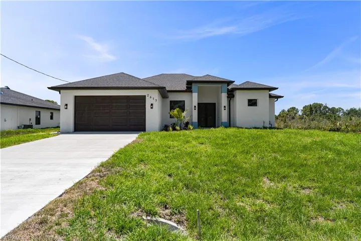 Prairie-style house with stucco siding, an attached garage, driveway, and a front yard