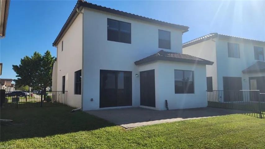 Two-story stucco residence featuring a tile roof and multiple windows