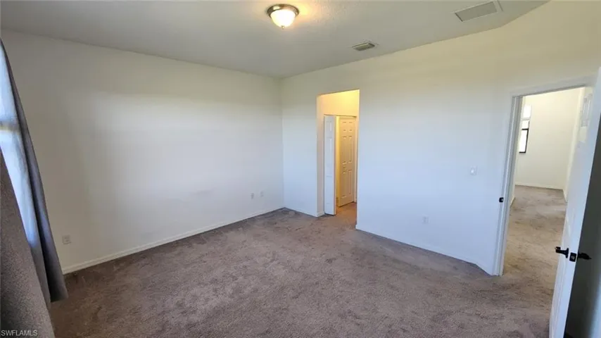 Spacious room with plush carpet flooring, neutral wall paint, and white trim
