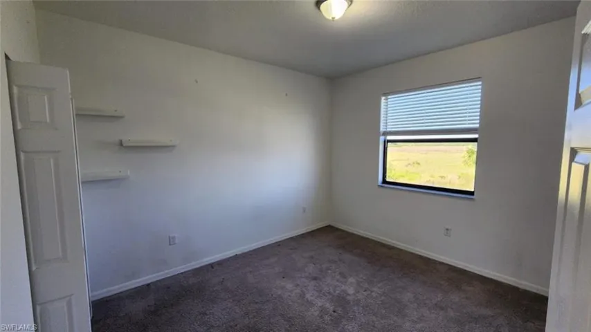 Interior room with neutral wall paint and dark carpet flooring