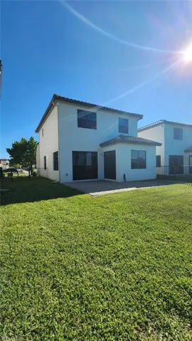 Rear exterior featuring a two-story design with a stucco finish and a tile roof