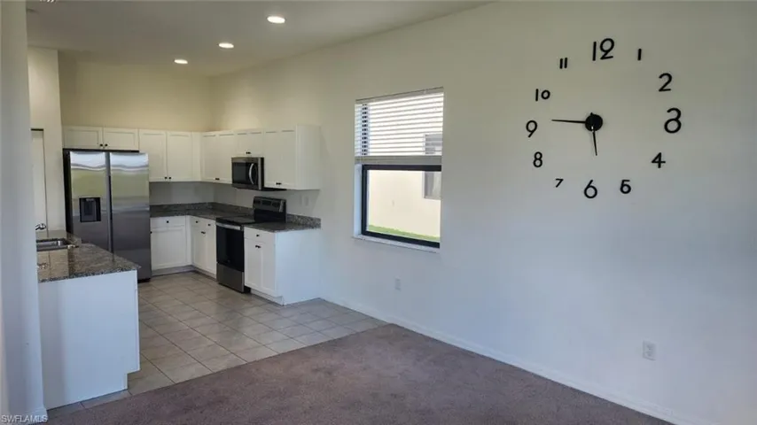 Open-concept kitchen featuring white cabinetry, stainless steel appliances, granite-style countertops, and recessed lighting