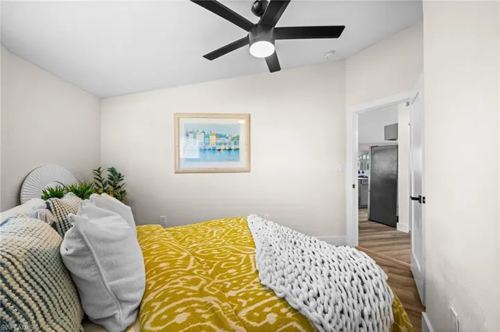 Bedroom with vaulted ceiling, wood finished floors, and a ceiling fan