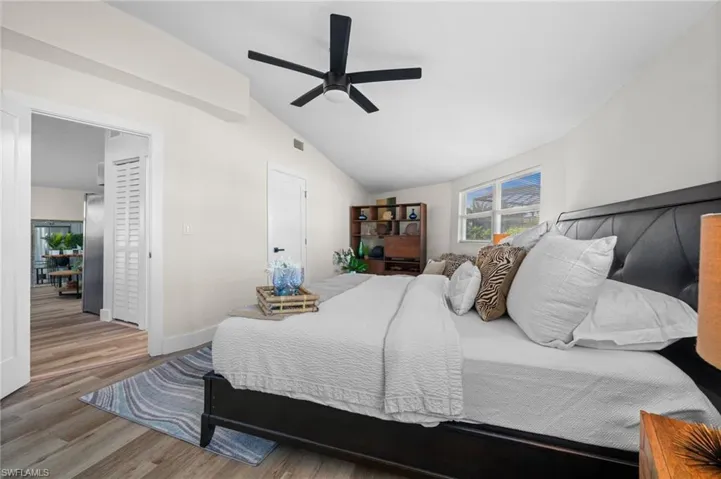 Bedroom with vaulted ceiling, wood finished floors, and ceiling fan