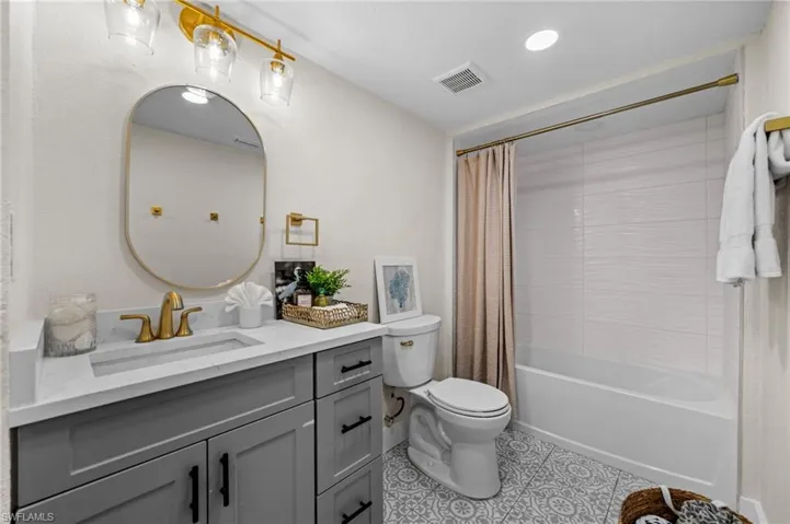 Full bath featuring vanity, shower / bath combo with shower curtain, and light tile patterned flooring