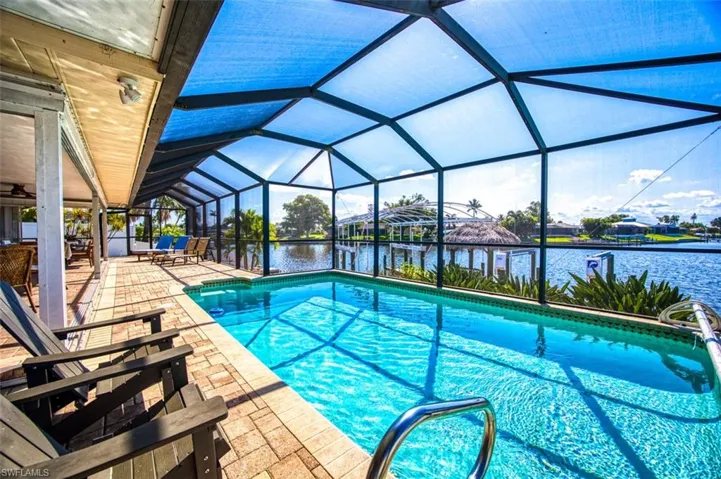 View of swimming pool featuring a patio, glass enclosure, and a water view