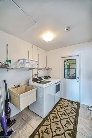 Laundry area with independent washer and dryer, sink, hookup for a washing machine, and light tile floors