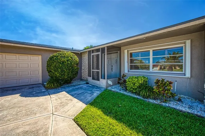 Doorway to property featuring a garage and a yard
