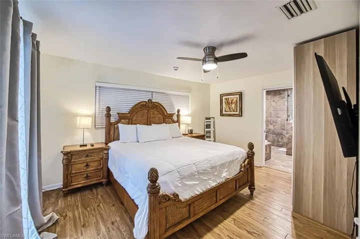 Bedroom with wood-type flooring, ceiling fan, and ensuite bath