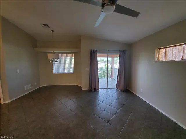 Spare room featuring lofted ceiling, dark tile patterned flooring, a chandelier, and a ceiling fan