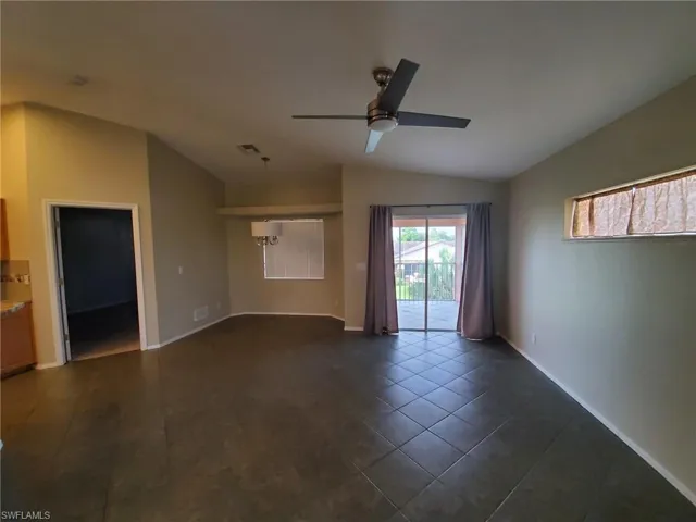 Unfurnished room featuring vaulted ceiling, dark tile patterned flooring, and a ceiling fan