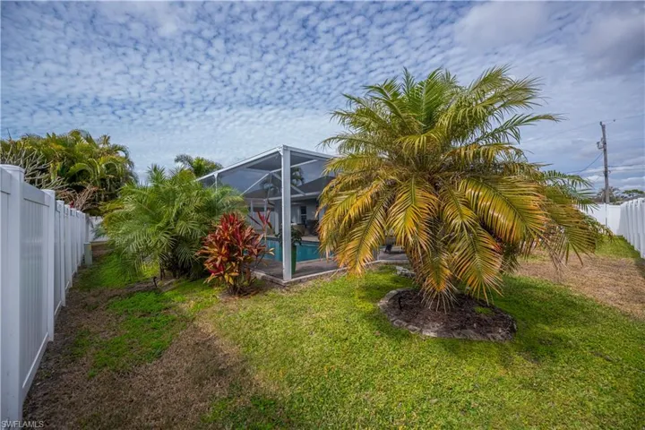 Fenced backyard featuring a sunroom and a lanai