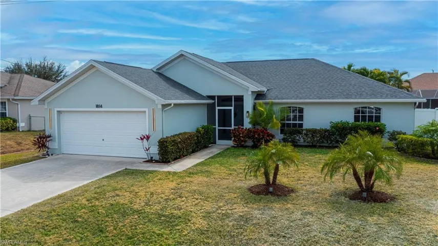 Ranch-style home with stucco siding, a sunroom, concrete driveway, an attached garage, and a front lawn