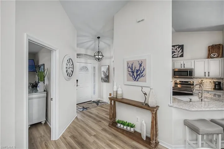 Foyer entrance featuring light wood finished floors, suspended lighting, and a high ceiling