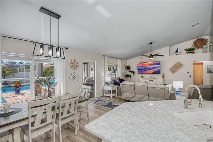 Dining space featuring light wood-style flooring, lofted ceiling, and a ceiling fan