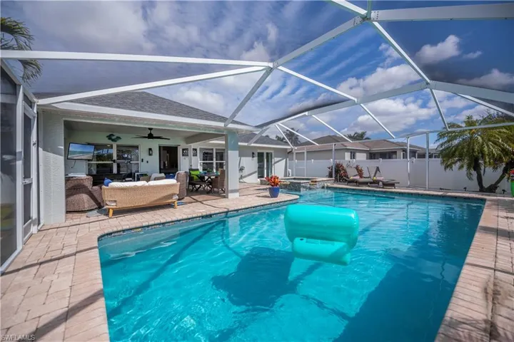 Relaxing pool / spa featuring a patio area, a sunroom, a lanai, and an outdoor living / dining area