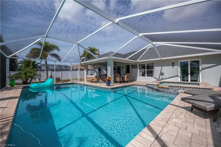Relaxing pool / spa with a sunroom, a patio area, a lanai, and outdoor dining space