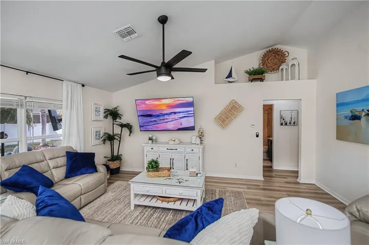 Living room featuring lofted ceiling, wood finished floors, and ceiling fan