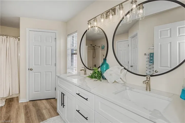 Full bath with light wood-type flooring, double vanity, and a shower with curtain