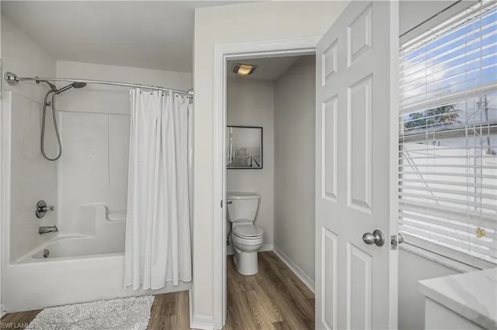 Bathroom with shower / tub combo and dark wood-type flooring