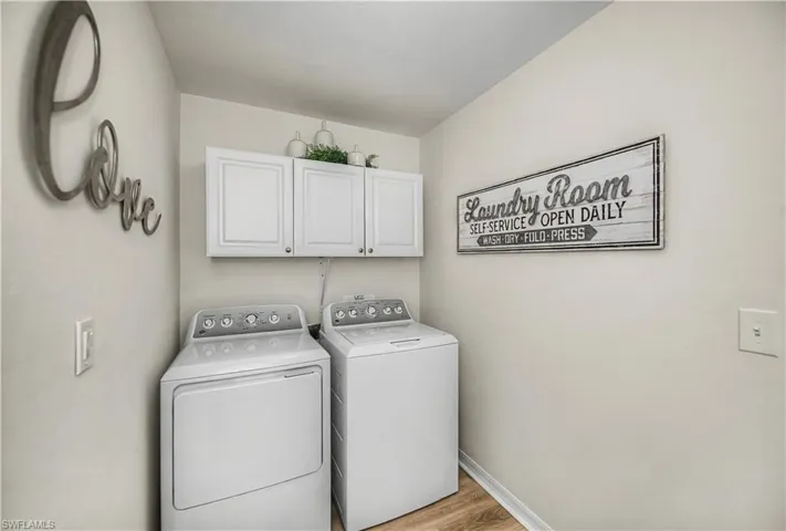 Laundry area with cabinet space, light wood finished floors, and washer and clothes dryer