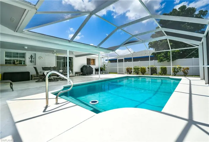 View of swimming pool with glass enclosure, a patio area, a sunroom, and grilling area
