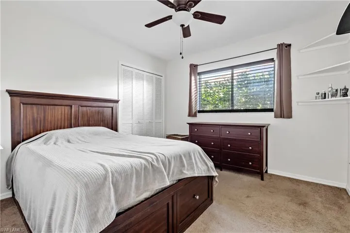 Bedroom featuring light colored carpet, a ceiling fan, and a closet