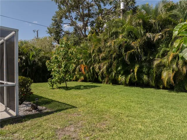 View of grassy yard featuring a sunroom and glass enclosure