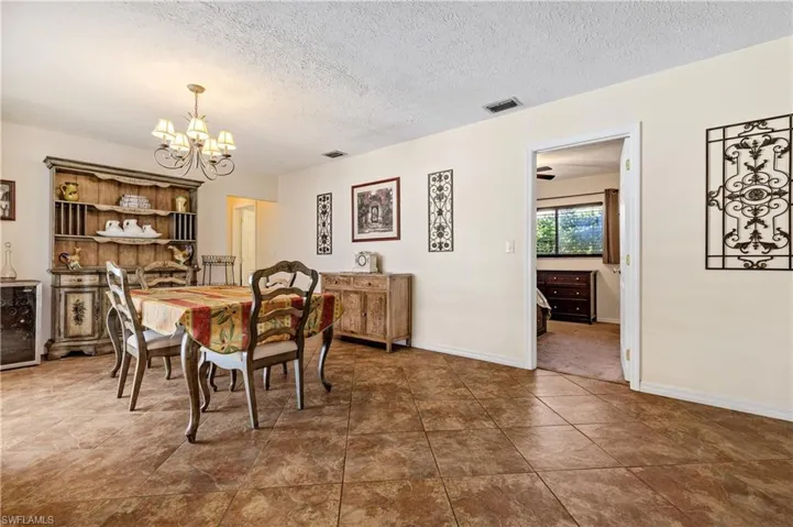 Dining area featuring wine cooler, a textured ceiling, and a chandelier