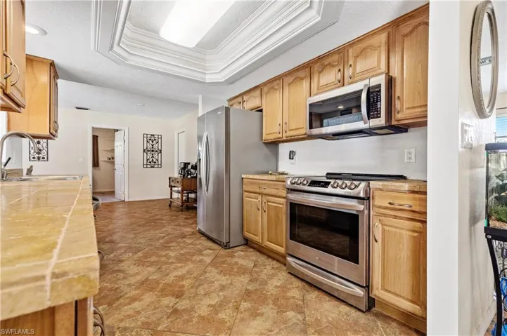 Kitchen with appliances with stainless steel finishes, crown molding, light countertops, a raised ceiling, and a textured ceiling