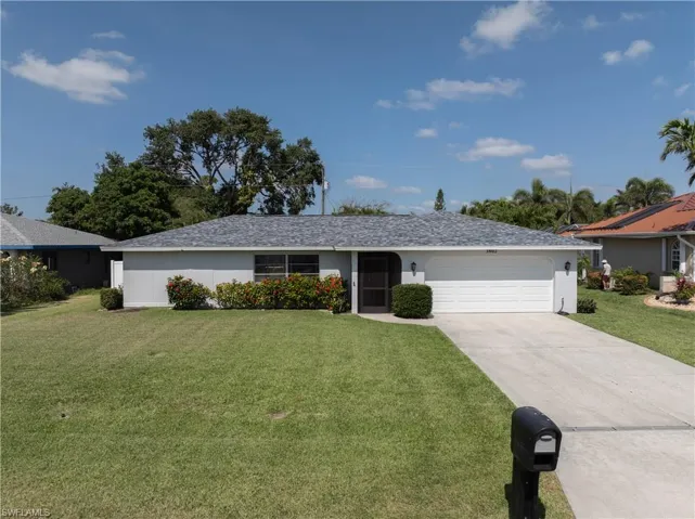 Ranch-style house with concrete driveway, a front lawn, an attached garage, and stucco siding