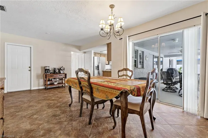 Dining space with a textured ceiling, a ceiling fan, and a chandelier