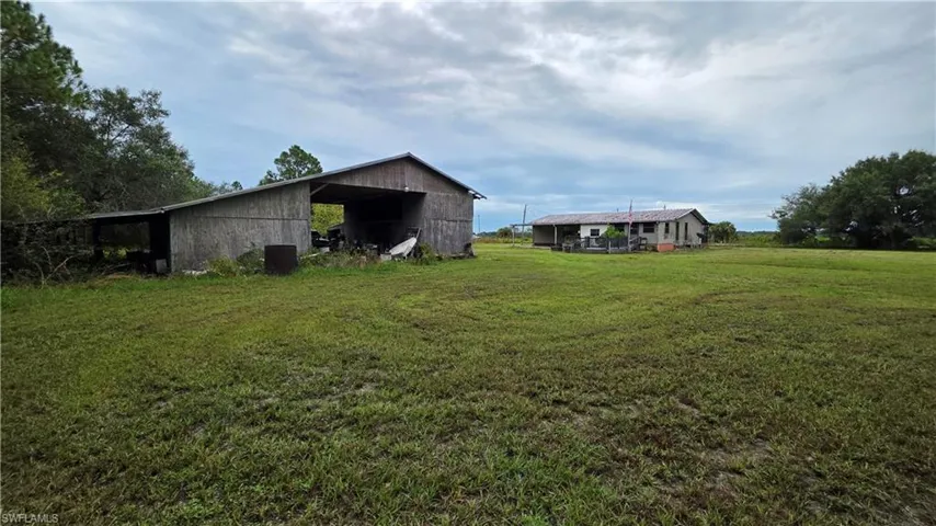 Expansive green space featuring a barn structure and a single-story residence with a covered porch