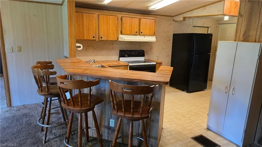 Kitchen featuring wood-finish cabinetry, built-in range, and a breakfast bar with wood-finish countertop
