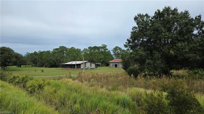 Expansive grassy area with a single-story residence featuring a screened porch