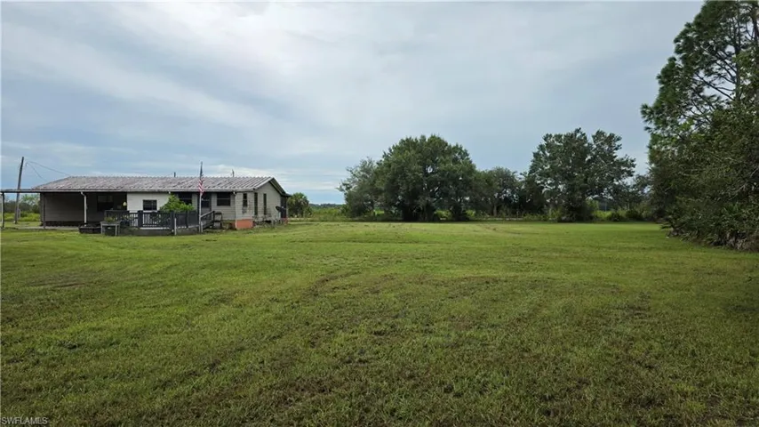 Expansive green space featuring a single-story residence with a covered porch and an extended deck