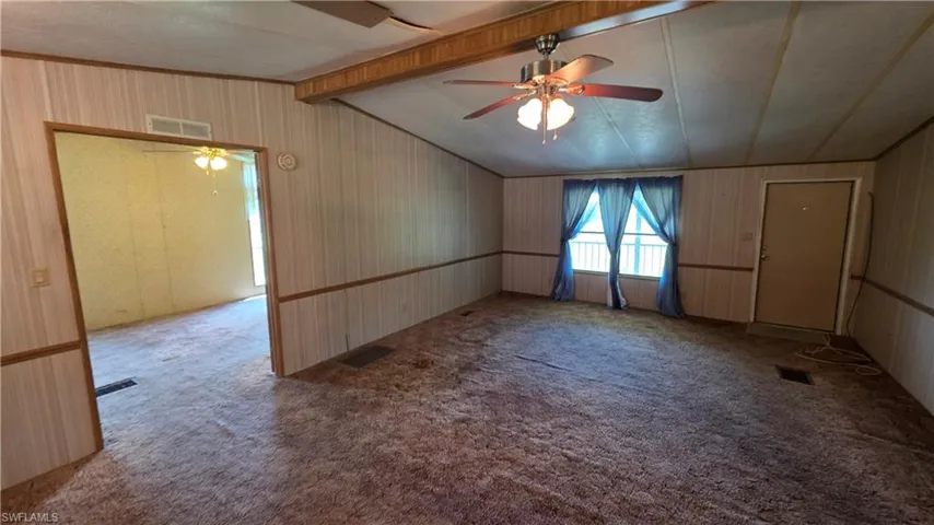 Interior space featuring wall paneling, ceiling fan, and carpeted flooring