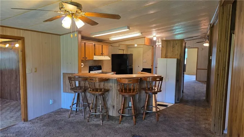 Kitchen with wood-finish cabinetry, black appliances, and a breakfast bar