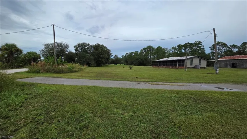 Single-story residence with a screened-in porch and an adjacent outbuilding, set on a grassy lot with mature trees