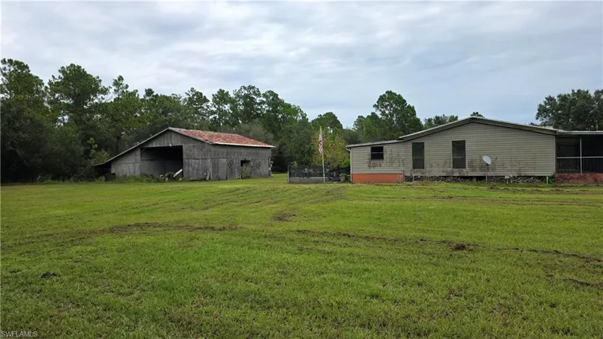 Expansive green space with an outbuilding and a residence featuring siding