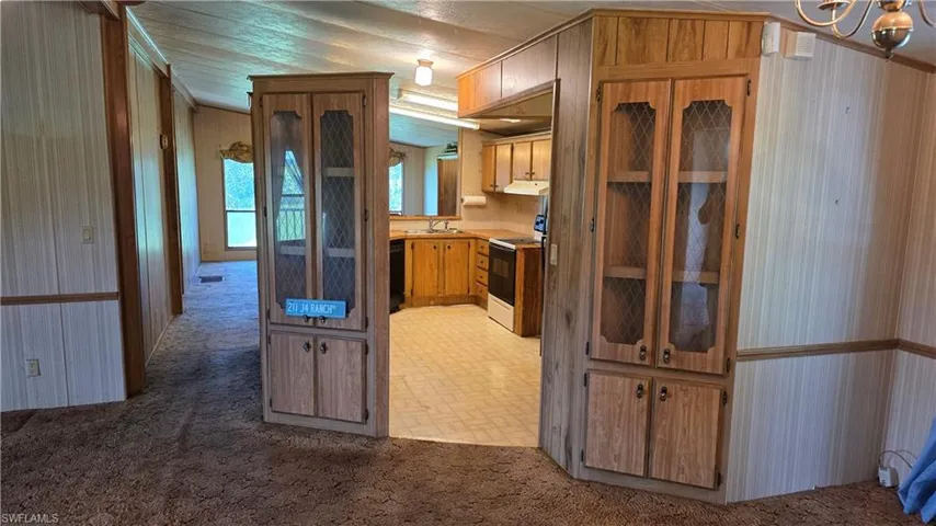 Built-in cabinetry with glass-front display, wood-finish paneling, and vinyl flooring