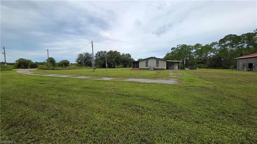 Expansive rural property featuring multiple outbuildings, mature tree line, and lush green acreage ideal for agricultural or recreational use