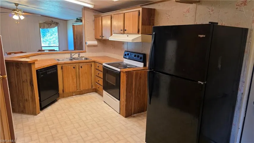 Kitchen featuring wood-finish cabinetry, built-in dishwasher, electric range, and laminate countertops
