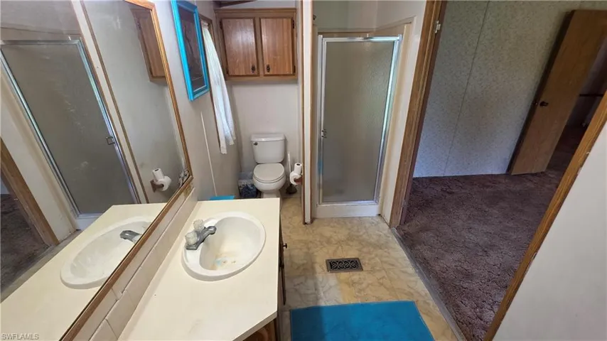 Bathroom featuring a vanity with an integrated sink, a toilet, and a glass-enclosed shower