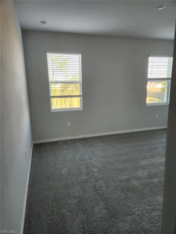 Unfurnished room with dark carpet and baseboards
