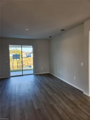 Empty room with dark wood-type flooring and recessed lighting