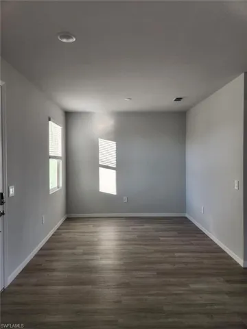 Empty room with dark wood-style floors and baseboards
