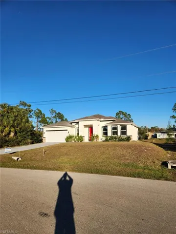 Ranch-style home featuring a front yard, an attached garage, concrete driveway, and stucco siding